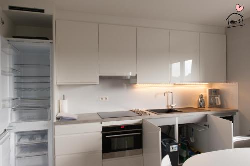 eine weiße Küche mit einer Spüle und einem Kühlschrank in der Unterkunft De Vlier - Vakantiewoningen in Maasmechelen