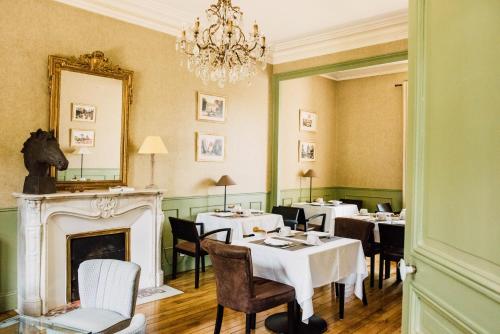 a dining room with tables and chairs and a fireplace at L'Hôtel Particulier Ascott in Saint Malo