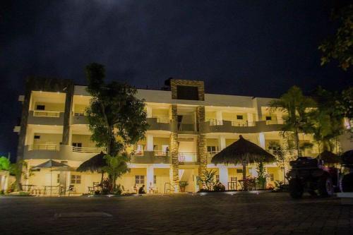 a large white building with trees in front of it at Real del Sol in Rincon de Guayabitos