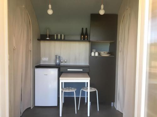 a small kitchen with a table and two stools at Saint Paul le Marseillais Tentes Equippees Hébergements Insolites Lodges in Mèze