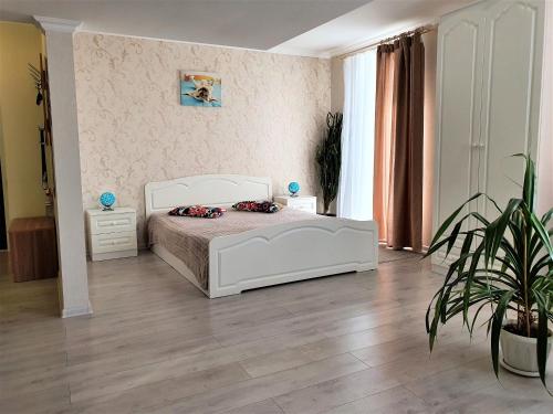 ヴォロネジにあるMEGAPOLIS улица Большая Манежная 13-В-77の白いベッドと鉢植えの植物が備わるベッドルーム1室