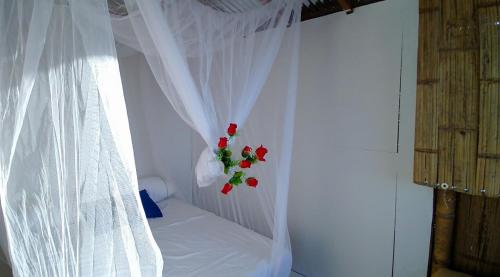 a bed with a white curtain and red flowers at biohotel tatacoa Qji in Villavieja