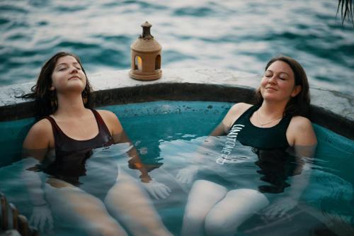 two women sitting in a hot tub in the water at Hotel La Casa del Mundo in Jaibalito