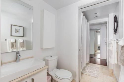 a white bathroom with a toilet and a sink at Two BD CN Tower and Lake Ontario View in Toronto