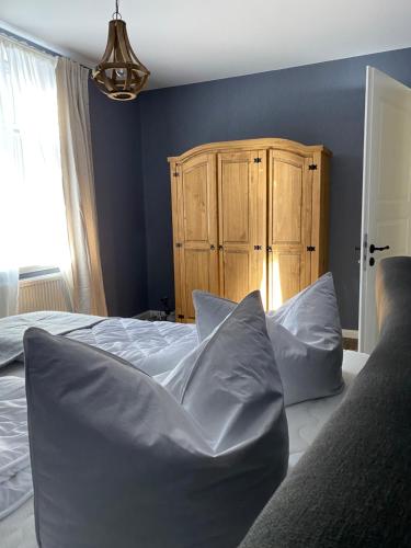 a bedroom with a bed with pillows and a wooden cabinet at Auszeit-Appartement Wernigerode in Wernigerode