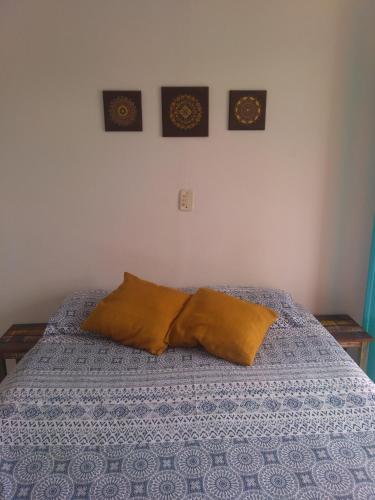 a bed with two pillows and two pictures on the wall at Pousada Gaucha Caiobá in Matinhos