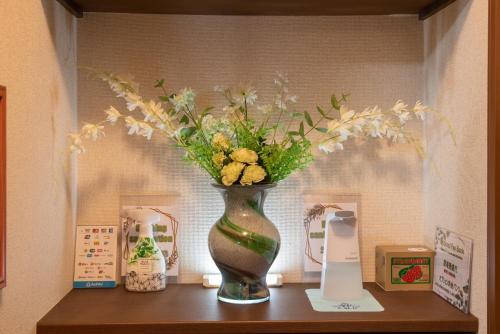 a vase filled with flowers sitting on a shelf at Garden Nikko Guest House in Nikko