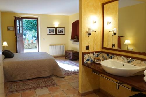 Schlafzimmer mit einem Bett, einem Waschbecken und einem Spiegel in der Unterkunft La Sala de Camós in Camós
