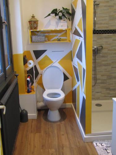 a bathroom with a toilet with a geometric wall at Chambre d'hôtes Au Nid du Thil in Beauvais