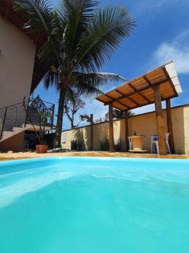 a swimming pool in front of a house with a palm tree at Suítes Canola in Ubatuba