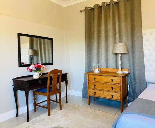 een slaapkamer met een bureau, een bed en een spiegel bij Bonne Chance Cottage in Paarl