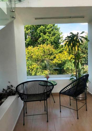 two chairs and a table on a balcony with a window at Rancho Macloy Hotel Spa & Social Events in Yautepec