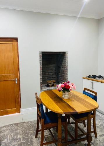 a dining room table with flowers on it with a fireplace at Bonne Chance Cottage in Paarl