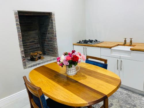 a kitchen with a wooden table with a vase of flowers on it at Bonne Chance Cottage in Paarl