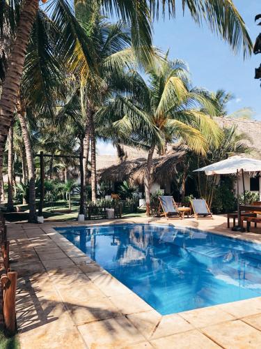 a swimming pool with palm trees in a resort at Paredon Surf House in El Paredón Buena Vista
