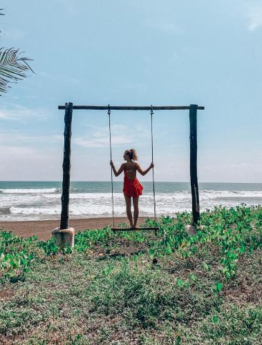 a woman standing on a swing at the beach at Paredon Surf House in El Paredón Buena Vista
