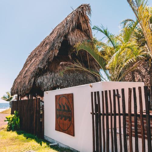 a hut on the beach with a fence and a gate at Paredon Surf House in El Paredón Buena Vista