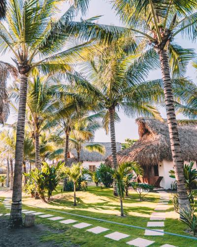 a group of palm trees in front of a house at Paredon Surf House in El Paredón Buena Vista