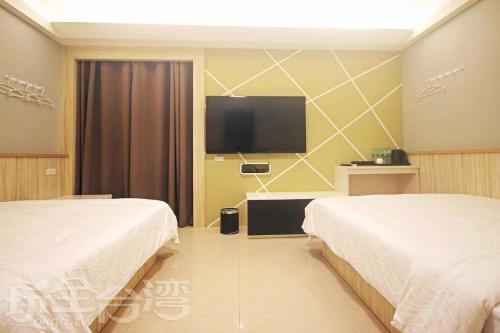a hotel room with two beds and a flat screen tv at 樂客2館 in Hsia-shih