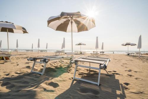 a beach with tables and umbrellas on the sand at Sabbia & Mare in Rosolina Mare