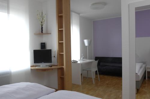 a bedroom with a bed and a desk with a television at Hotel am alten Park in Augsburg