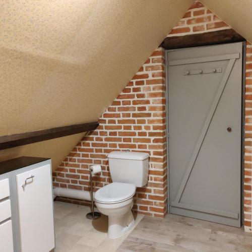 a bathroom with a toilet in a brick wall at La Renardie in La Ferté-Imbault