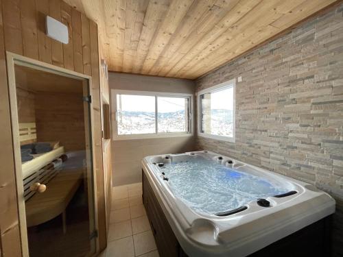 un bagno con ampia vasca e finestra di le bleu du lac Sauna et Spa a Gérardmer