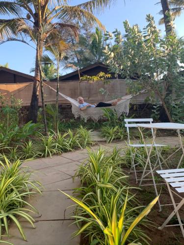 a man laying in a hammock in a garden at The Village Anjuna in Anjuna