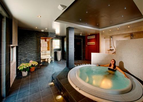 a woman in a large bath tub in a room at Hotel Restaurant L'Ami Fritz in Ottrott