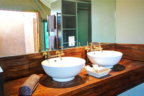 baño con 2 lavabos blancos en una encimera de madera en Fathala Wildlife Reserve, en Toubakouta