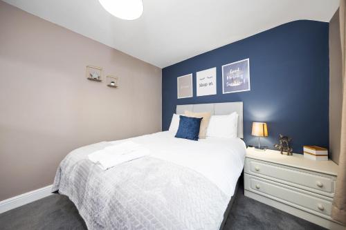 a bedroom with a white bed and a blue wall at Inspire Homes - Joe's Cottage in Southam