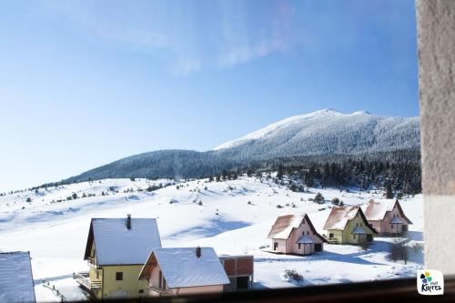 a group of houses in the snow with a mountain at Apartman Adria 2 in Kupres