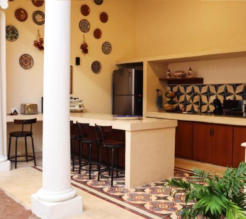 a kitchen with a counter with stools and a refrigerator at Hotel & Hostal Boutique Casa Garza in Mérida