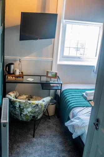 a bedroom with a bed and a desk and a window at Abbey Court Guest House in Carlisle
