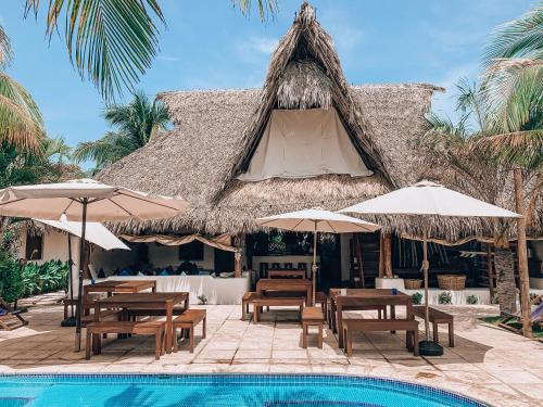 un complejo con piscina, mesas y sombrillas en Paredon Surf House, en El Paredón Buena Vista