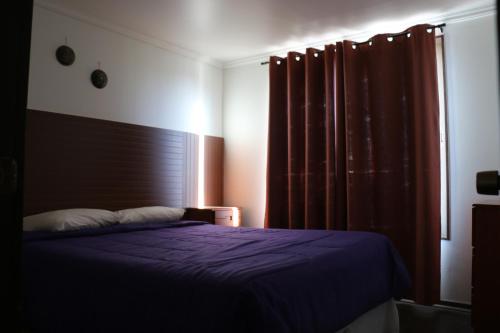 a bedroom with a purple bed and a window at Cabañas Kakanchik in Vicuña