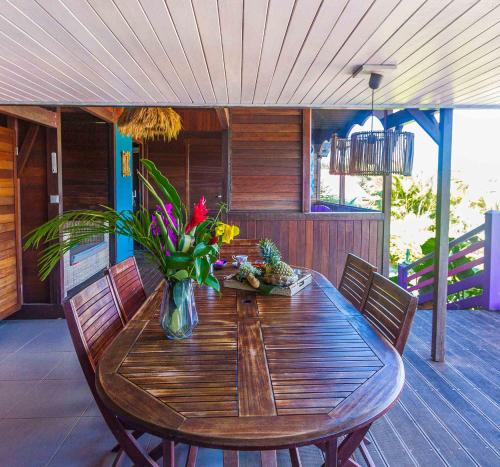 a wooden table with a vase of flowers on a deck at Piton Bungalows Ecolodges in Deshaies
