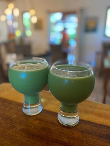two green glasses sitting on top of a table at Casa Hridaya Hotel Boutique in Holbox Island