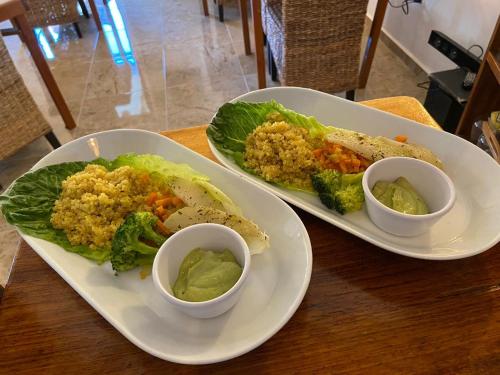two plates of food with rice and broccoli on a table at Casa Hridaya Hotel Boutique in Holbox Island