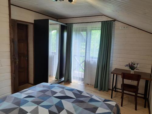 1 dormitorio con cama, mesa y ventanas en Під Боржавою en Pilipets