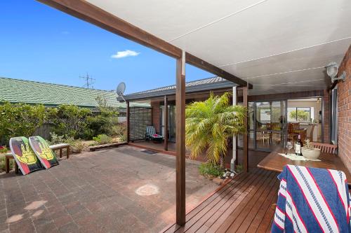 an open deck with chairs and a house at Bream Bay Bach - Ruakaka Holiday Home in Ruakaka