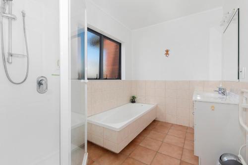 a bathroom with a tub and a sink and a window at Bream Bay Bach - Ruakaka Holiday Home in Ruakaka