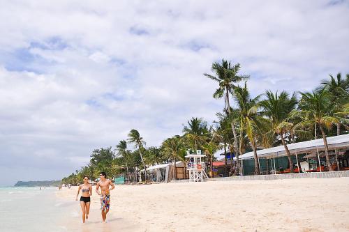 two people walking on the beach near the ocean at Paradise Garden Hotel and Convention Center Boracay Powered by ASTON in Boracay
