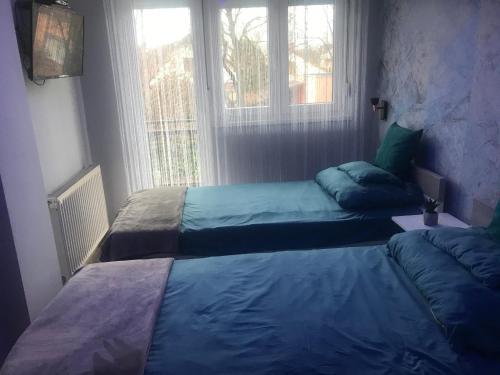 two beds in a room with a window at Annabella Vendégház in Hajdúszoboszló