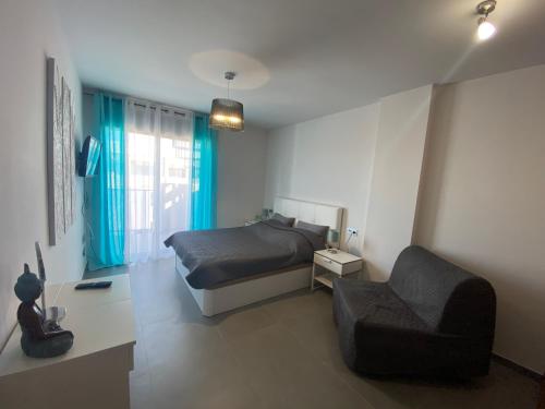 ein Schlafzimmer mit einem Bett und einem Stuhl darin in der Unterkunft New and cosy apartment - 4 min walk from the beach - La Tejita - El Medano in Granadilla de Abona