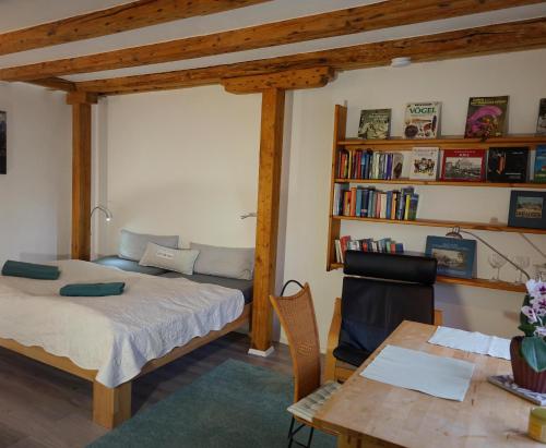 a bedroom with a bed and a table and bookshelves at "Haus auf dem Berg" in Westensee