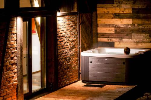 a bathroom with a tub and a brick wall at Novosiele Lifestyle Apartments in Bystre