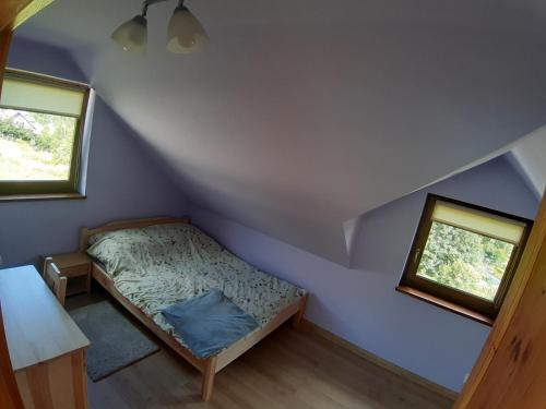 a small bedroom with a bed and two windows at Górskie Zacisze Kamienica in Stronie Śląskie