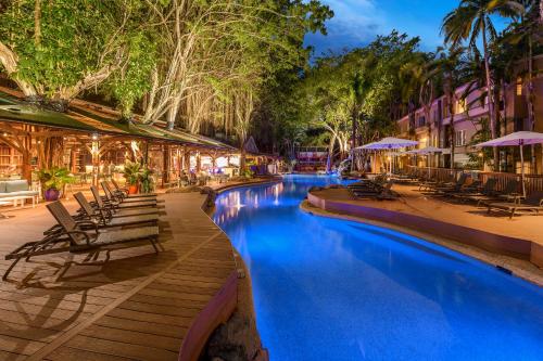 a resort swimming pool with lounge chairs and umbrellas at Ramada Resort by Wyndham Port Douglas in Port Douglas