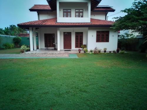 a house with a green lawn in front of it at NegomboVilla in Negombo